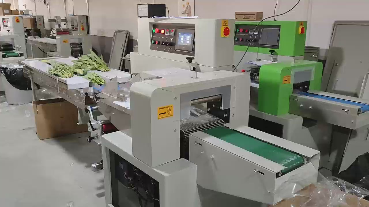 Demonstrates the Keypack Intelligent KL-800XDSF wide-format bottom film horizontal flow wrapping machine overwrapping fresh vegetable trays and produce bundles. Features triple-servo motor control with PLC automation, fiber-optic product detection for automatic cycle initiation, and independent PID temperature sealing for PE and perforated breathable films. Operates at 5–20 meters/min with max film width 790mm and product height up to 100mm, accommodating standard produce trays and boxed vegetable packs. 