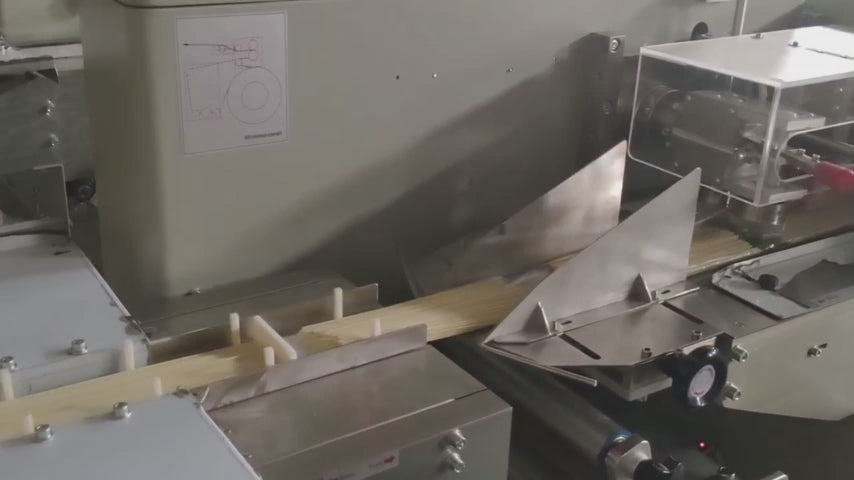 Demonstrates the Keypack Intelligent KL-350 bottom film horizontal flow wrapping machine packaging instant noodle blocks into pillow bags. Features three-servo motor control with PLC automation, fiber-optic product detection for automatic cycle initiation, and high-sensitivity photoelectric color mark tracking for precise seal and cut positioning. Operating at 5–25 bags/min with max film width 340mm and bag width 50–160mm. Suitable for instant noodle block flow wrapping, dried noodle horizontal packaging, a
